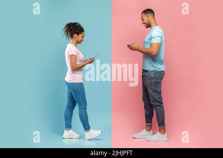 Modern technology and relationship concept. Black guy and lady using their smartphones, texting each other Stock Photo
