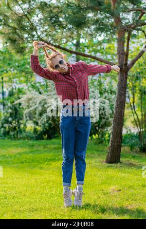 Cheerful woman lifts herself into the air by pigtails Stock Photo