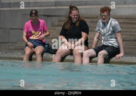 People with their feet in a fountain at Trafalgar Square in central London. Picture date: Tuesday July 19, 2022. Stock Photo