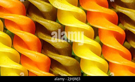 Uncooked raw tricolor macaroni pasta on black background. Macro food photo. Stock Photo