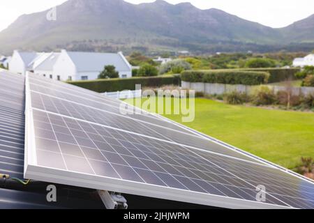 Solar panels on rooftop and scenic view of mountains and lush landscape against clear sky Stock Photo