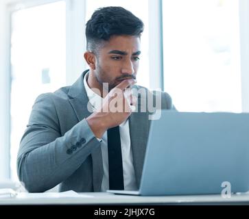 Putting careful consideration into every idea. a young businessman looking thoughtful while working on a laptop in an office. Stock Photo