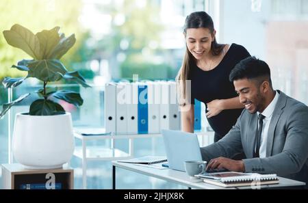 Finishing up right on time. two businesspeople working together on a laptop in an office. Stock Photo
