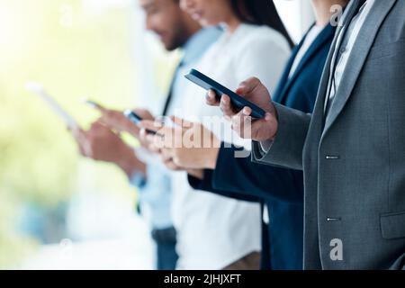 None of us is as smart as all of us. a group of unrecognizable businesspeople using their devices in a modern office. Stock Photo