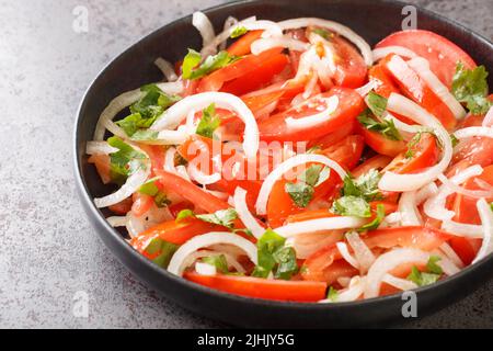 Concept healthy appetizer Fresh tomatoes with onion and spices closeup in the plate on the table. Horizontal Stock Photo