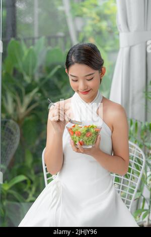 Healthy lifestyle woman eating salad smiling happy indoors on beautiful day Stock Photo