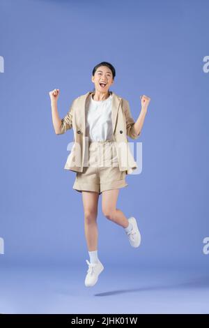 Full length body size photo of girlish cheerful woman jumping stepping smiling isolated purple background Stock Photo