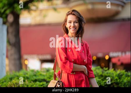 Portrait of an attractive brown haired woman wearing casual clothes while walking the street. Stock Photo