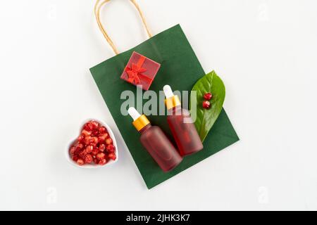 Red dropper bottles of pomegranate serum or oil for face and body lying on a white table Stock Photo