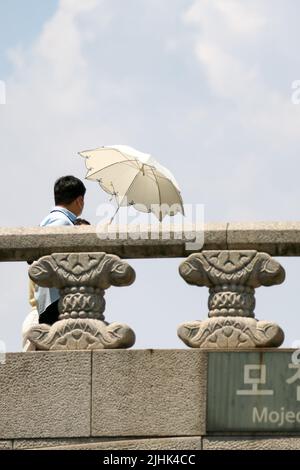 Seoul, South Korea. 19th July, 2022. People holding an umbrella walk on a bridge in Seoul, South Korea, July 19, 2022. Credit: Wang Yiliang/Xinhua/Alamy Live News Stock Photo