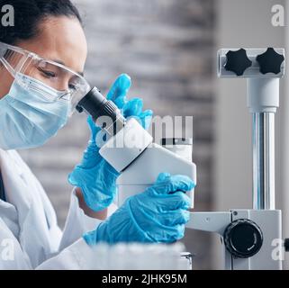 Notices the changes as they appear. a young scientist using a microscope in a lab. Stock Photo