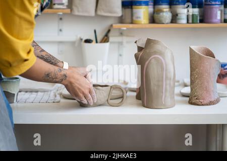 Female ceramist making mug in studio, woman working with clay during pottery masterclass Stock Photo