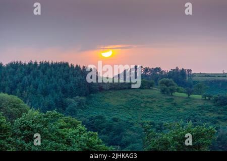 A ball of sun setting over the fields in the Brecon Beacons, South Wales UK Stock Photo