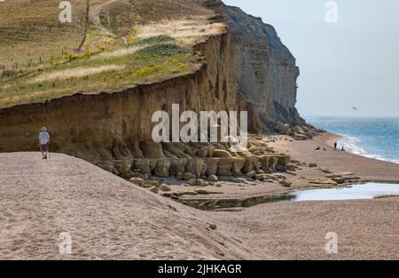 Dorset, England, United Kingdom, 19th July 2022. UK Weather: heatwave. A sea breeze makes the temperature bearable on the hottest day of the year along the Jurassic coast at Burton Freshwater. An elderly man walking on the beach with a walking stick Stock Photo