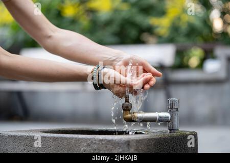 Hydration and aqua balance regulation for health. Hands with water pouring from tap in street. Stock Photo