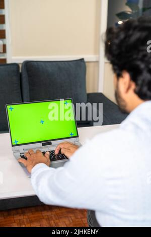 Vertical shoudler shot of corporate employee busy working on laptop with green screen mock up - concept of software developer, white collar jobs and Stock Photo