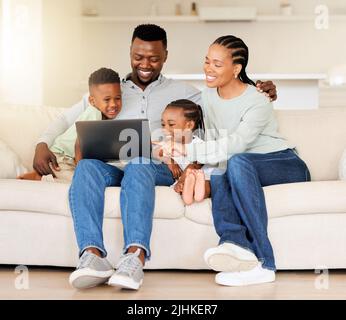 Happy young african american family sitting together and using laptop. Curious cute little girl and boy sitting with their parents and learning Stock Photo