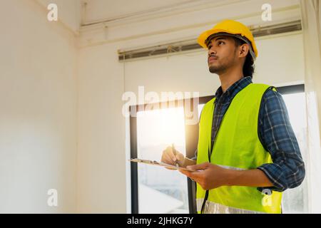 Asian inspector wear safety vest and checking list into clipboard, Architect Checking Insulation During House Construction Stock Photo