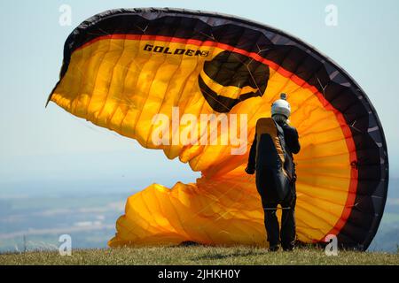 Kozakov, Czech Republic. 19th July, 2022. A Paraglider prepare to take off from Kozakov hill (100 kilometers north from Prague) during sunny day in the Bohemian Paradise in the Czech Republic. Paragliding is a recreational and competitive flying sport. The pilot sits in a harness suspended below a fabric wing, whose shape is formed by the pressure of air entering vents in the front of the wing. (Credit Image: © Slavek Ruta/ZUMA Press Wire) Stock Photo