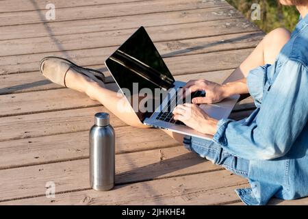 Side view of unrecognizable young man with straight leg working on his online job in natural enviroment Stock Photo