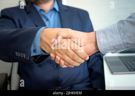 man handshake with hr manager after job interview in office. Attractive male employee shake hands with human resources manager businessman after apply Stock Photo