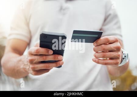 Closeup of unknown mixed race tennis player using cellphone and credit card on court. Hispanic fit athlete paying for sports membership on a phone in Stock Photo