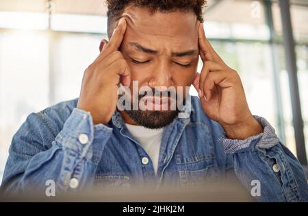 Young man looking stressed with a headache at home. Man feeling anxious with a migraine at home. Depressed young man with a headache at home. bachelor Stock Photo