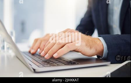 Closeup of caucasian businessman typing on a laptop keyboard in an office. Hands of one entrepreneur pressing buttons to send email and browse the Stock Photo