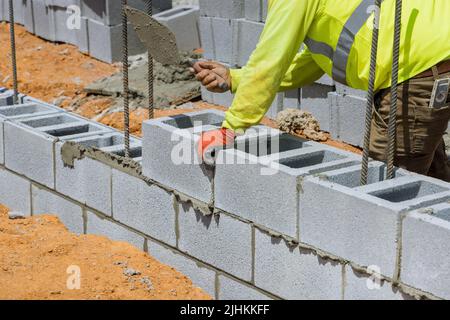Mason Using Blocks A mason is in the process of mounting a wall of aerated concrete blocks ...