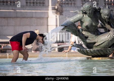 London, UK, 19/07/2022, London Heatwave A tourist cools off in one of the fountains at Trafalgar Square today as temperatures reach 37C in some of the hottest weather to ever hit the United Kingdom. 19th July 2022 London, UK Stock Photo