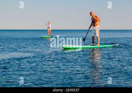 July 5, 2022. Dalaman, Turkey. Older couple on paddle board on blue sea. Stock Photo