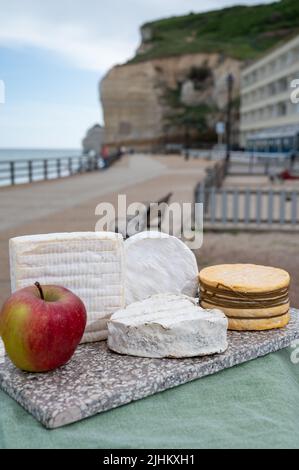 Four famous cheeses of Normandy, squared pont l'eveque, round camembert cow cheese, yellow livarot, heartshaped neufchatel and view on promenade and a Stock Photo