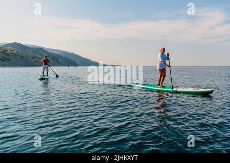 July 5, 2022. Dalaman, Turkey. Older couple on SUP board on blue sea. Active lifestyle for aged man and woman Stock Photo