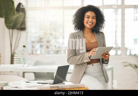Happy businesswoman using a digital tablet. Young leading businesswoman using a wireless tablet. Creative designer working in her agency. Designer Stock Photo