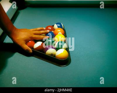 Hand preparing pool balls in triangle rack on the billiard table Stock Photo