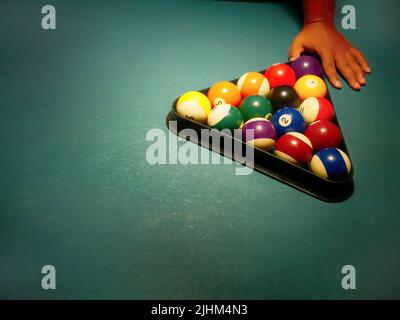 Hand preparing pool balls in triangle rack on the billiard table with copy space Stock Photo