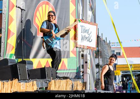 NEW ORLEANS, LA, USA - April 29, 2022: Richard Daley plays bass in front of Third World sign with woman standing by to give interpretive sign language Stock Photo