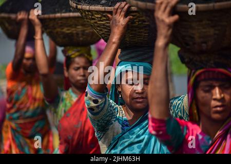 Women workers carrying baskets filled with coal on their head in the Gabtoli region of Dhaka Stock Photo