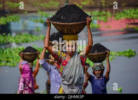 Women workers carrying baskets filled with coal on their head in the Gabtoli region of Dhaka Stock Photo