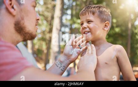 Let daddy help you. a handsome young man putting sunblock on his adorable little son while camping in the woods. Stock Photo