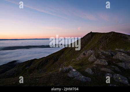 The summit crag of Coniston Old Man at dawn above a cloud inversion, in the English Lake District Stock Photo