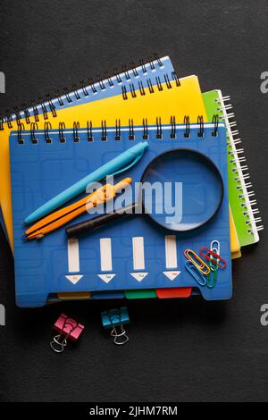 stack of notebooks and school supplies. School and education concept on black background Stock Photo