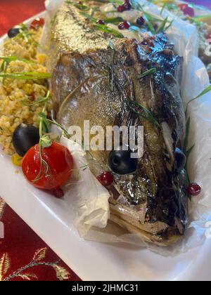 whole fish baked pike perch on a white platter close-up. Stock Photo
