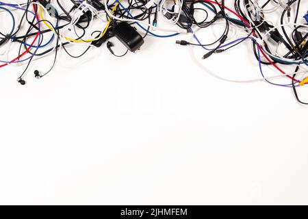 Many colorful electrical cord wires cables cord with plugs and electric socket on white background Stock Photo