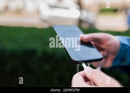 Close-up of male executive connecting headphones to smart phone. Midsection of businessman using audio equipment. He is preparing to listen music whil Stock Photo
