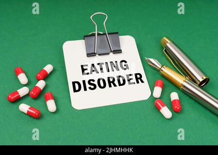 Medical concept. On the green surface of the tablet, a pen and a notepad with the inscription - Eating Disorder Stock Photo