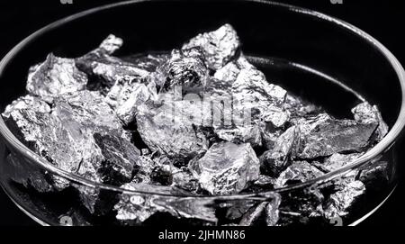 Chromium fragments, industrial use ore, metallic chemical element, isolated on black background inside a petri dish Stock Photo