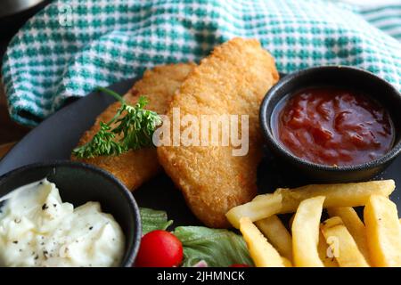 Crispy hake fillets with chips, tomato sauce and tartare sauce Stock Photo