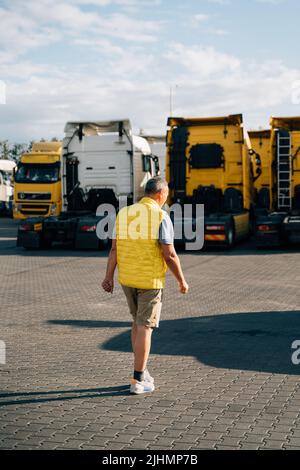 Portrait of caucasian mature man on semi-truck vehicles parking background. Truck driver worker  Stock Photo