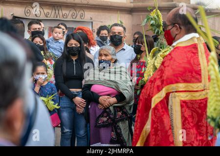 Worshippers watch as a procession carries a statue of Jesus Christ, into the Basílica de Nuestra Señora de la Salud, or Basilica of Our Lady of Health, in celebration of the traditional Palm Sunday service marking the start of holy week, April 10, 2022 in Patzcuaro, Michoacan, Mexico. Stock Photo